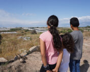immagine di tre ragazzini che guardano sconsolati i campi davanti a loro